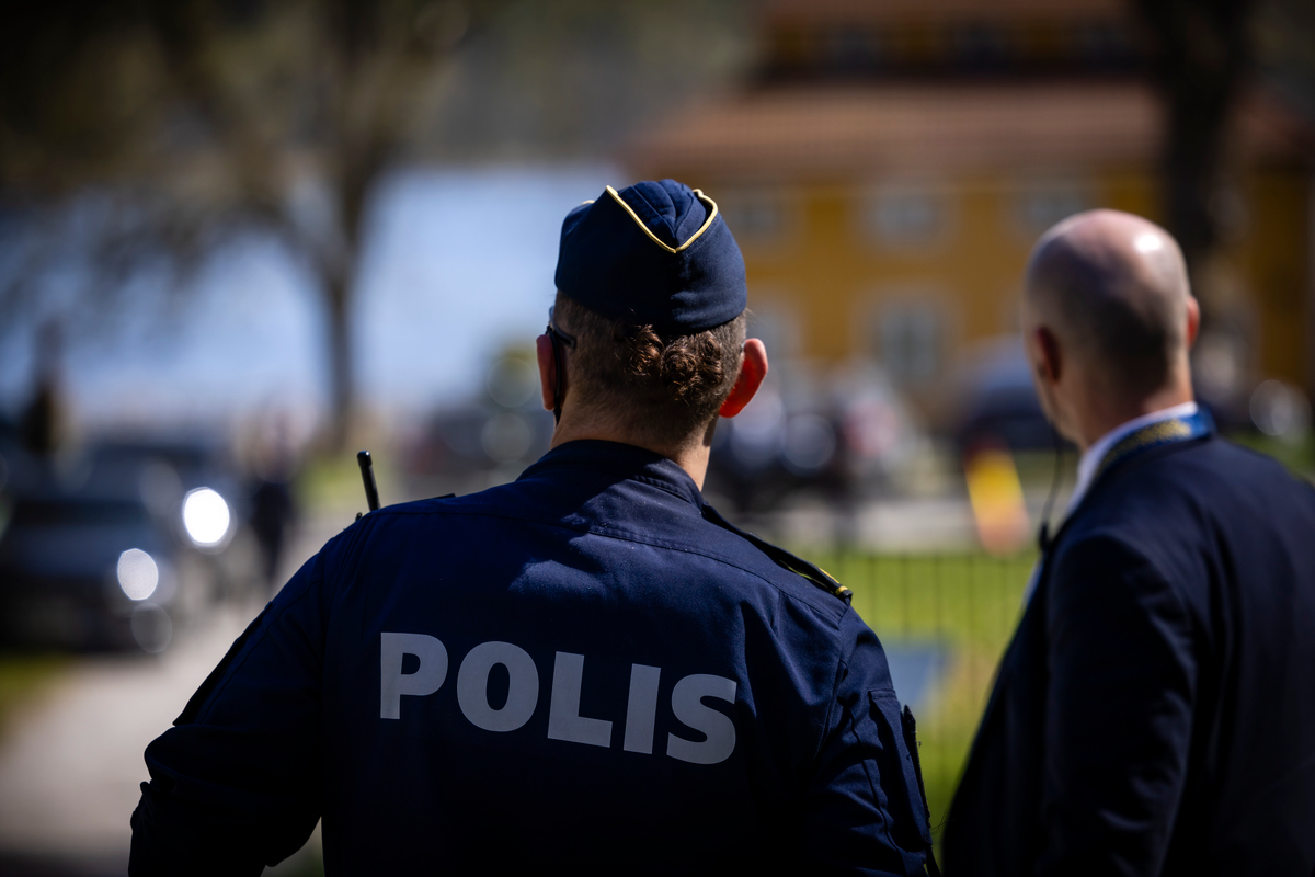 Livvakter och poliser samtalar utomhus.